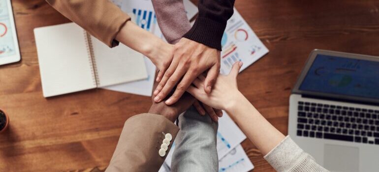 A close-up photo of people joining hands over a table.