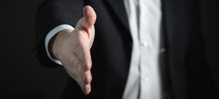 A man in a suit presenting his hand.