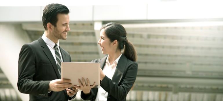 A businessman and businesswoman looking at laptop and smiling.