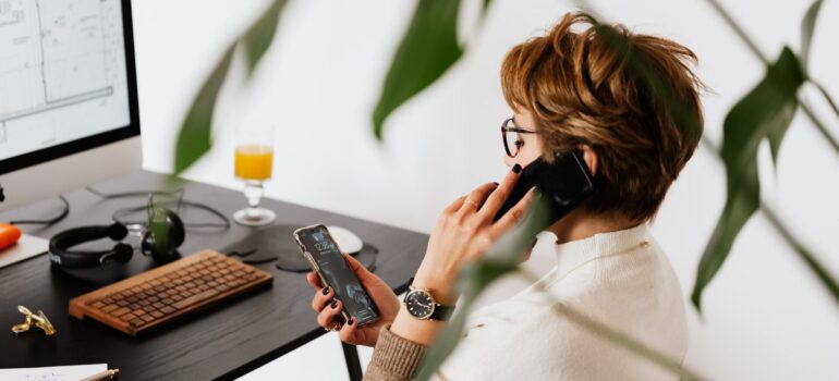 A sales agent trying to talk on a phone while looking at a different one.