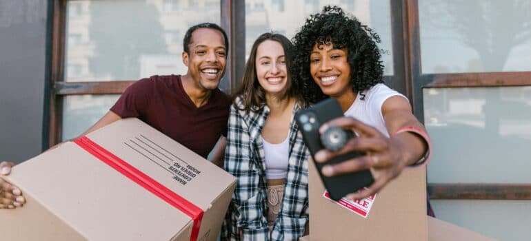 A mover smiling while taking a selfie with customers, showing that understanding your customers is one of the key lead generation tactics for small businesses.