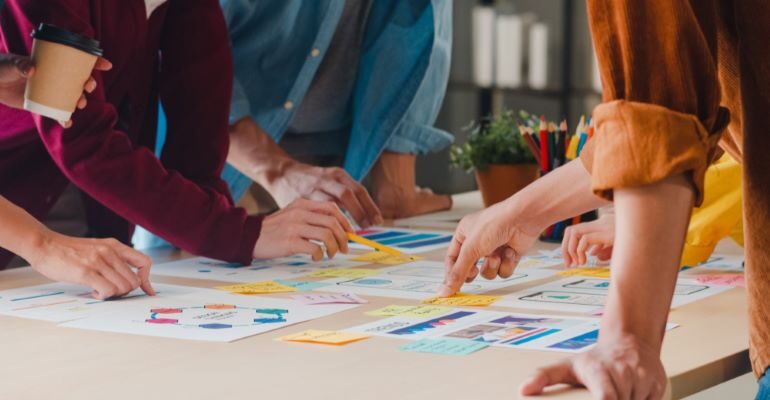 Group of people looking at different data and graphs on a large table.