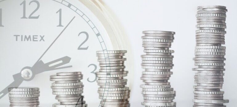 A clock and growing stacks of coins from left to right.