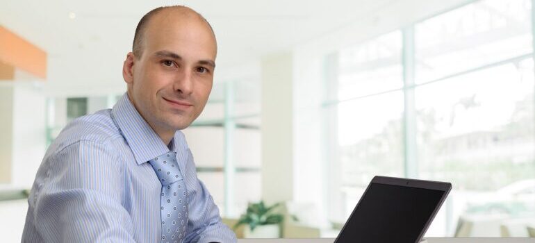 A smiling employee sitting in front of a laptop.