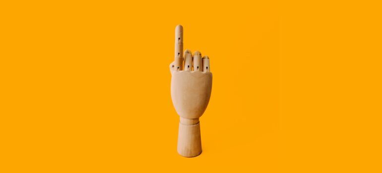 A wooden hand with the index finger pointing above.