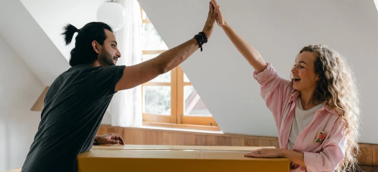 A happy couple joining hands over moving boxes.