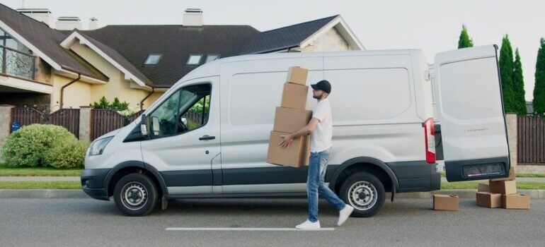 white moving van and a mover carrying boxes