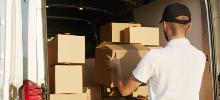 A person loading moving boxes to the moving truck.