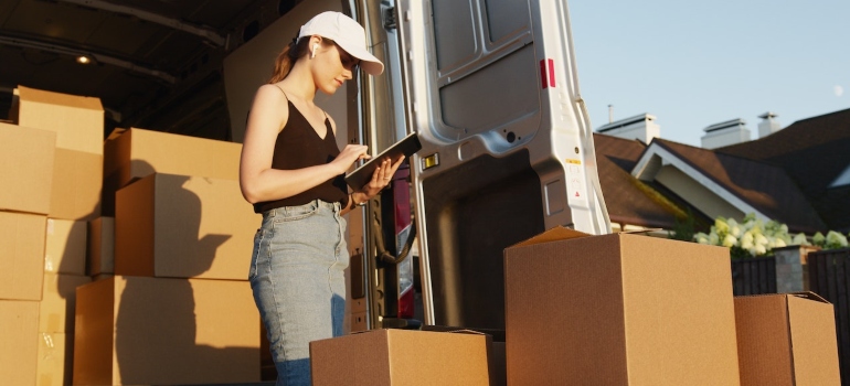 Professional mover standing next to moving boxes and managing student moves with CRM