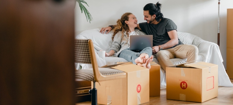 Couple sitting on a couch and researching role of moving CRM in digital marketing on a laptop