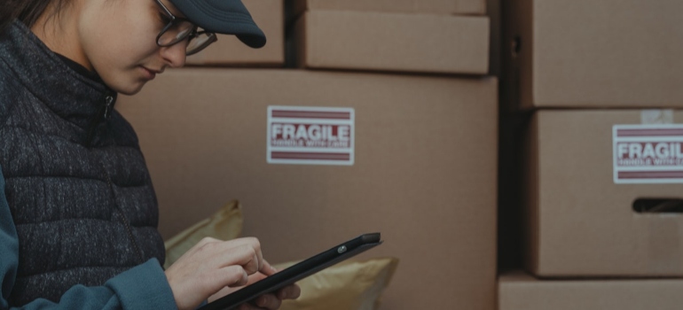 A woman checks lists on a tablet.