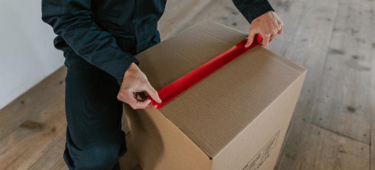 A man taping up the moving box.