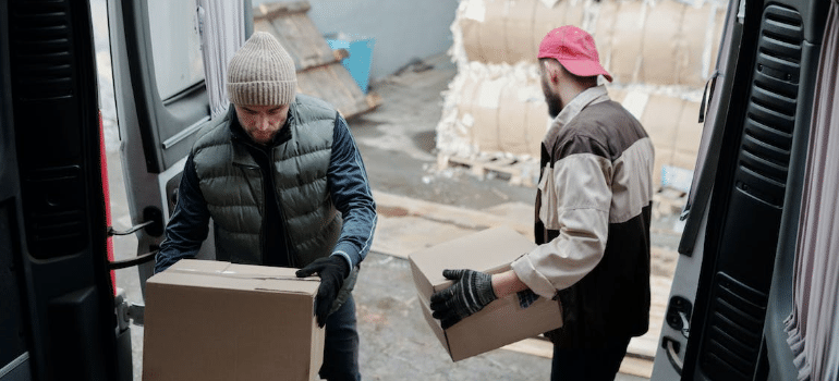 Two men unloading boxes from a truck