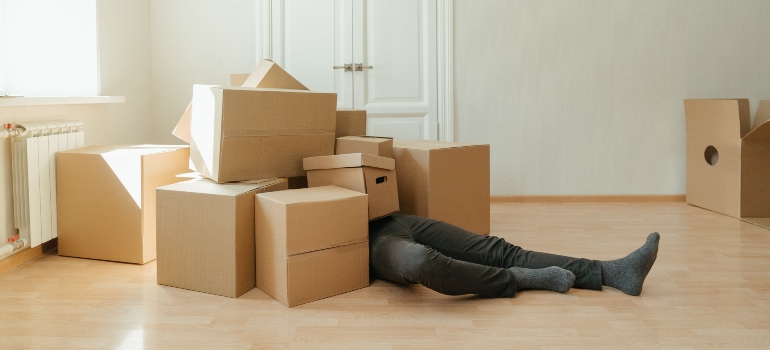 A man lying under a pile of boxes