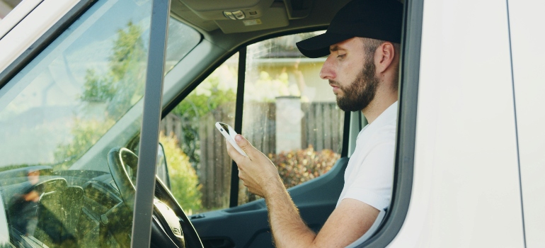 A mover looking at his phone in a van 