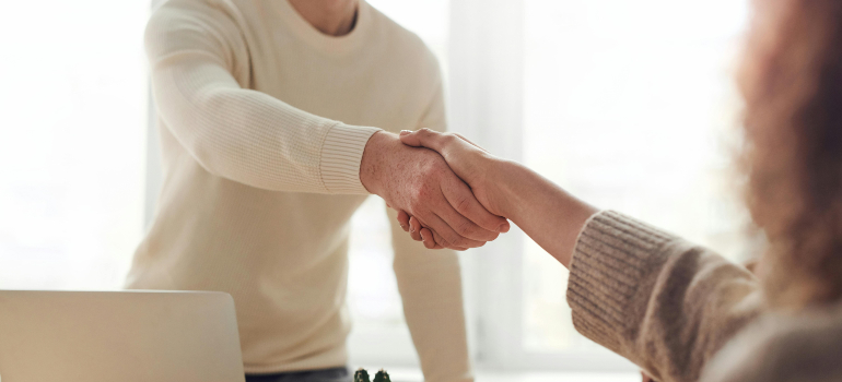 Moving company owner shaking hands with a happy customer